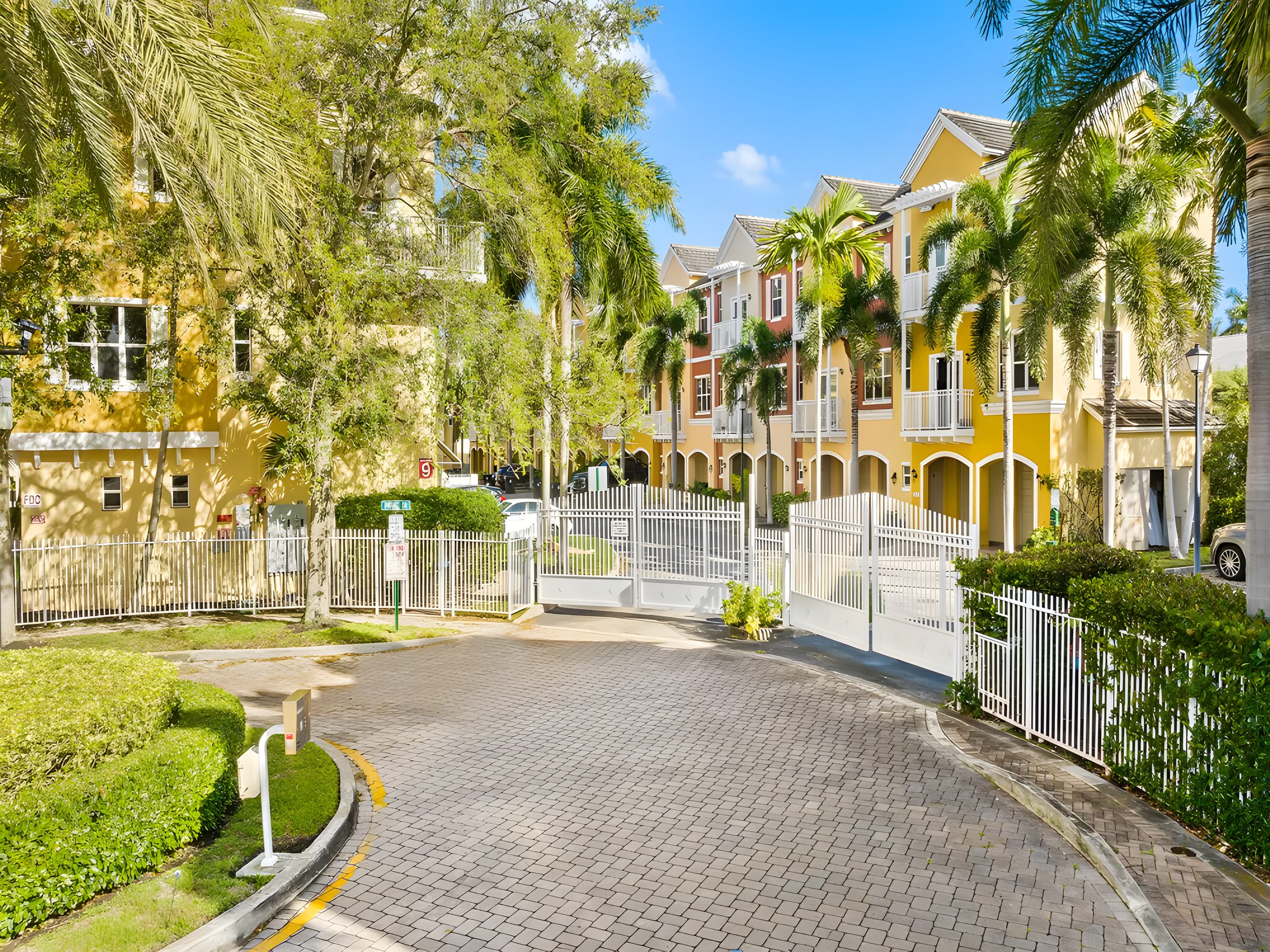 The gated entrance to Vintage at Lighthouse Point, with brick pavers and a white gate.